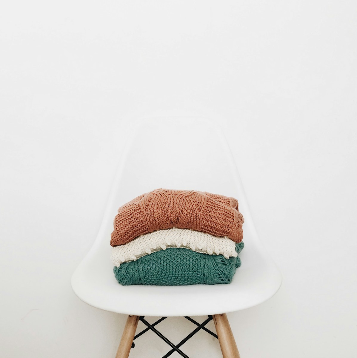 Photo by rocknwool three knit piles of clothes on white chair